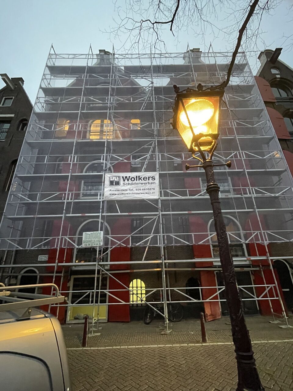 Steiger met Wolkers-doek voor een grachtenpand, 's avonds bij een straatlantaarn